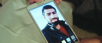 Movie still from “City of Ghosts” (2017), directed by Matthew Heineman – A person holding a cell phone in their hand; Extreme Close Up shot, Overhead angle