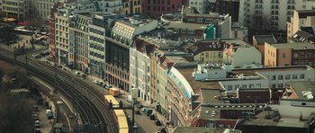Movie still from “City of Ghosts” (2017), directed by Matthew Heineman – An aerial view of a city with a train on the tracks; Extreme Wide shot, High angle