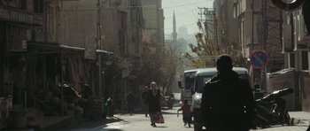 Movie still from “City of Ghosts” (2017), directed by Matthew Heineman – People walking down a street in a city; Extreme Wide shot, Low angle