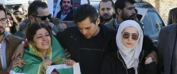 Movie still from “City of Ghosts” (2017), directed by Matthew Heineman – A group of people gathered around a man holding papers; Medium shot, High angle