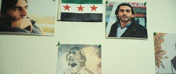 Movie still from “City of Ghosts” (2017), directed by Matthew Heineman – A picture of a man and a flag on a wall; Close Up shot, Low angle