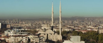 Movie still from “City of Ghosts” (2017), directed by Matthew Heineman – A view of a city with a mosque in the foreground; Extreme Wide shot, Low angle