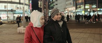 Movie still from “City of Ghosts” (2017), directed by Matthew Heineman – A man and a woman walking down a street; Close Up shot, Over the shoulder angle