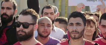 Movie still from “City of Ghosts” (2017), directed by Matthew Heineman – A group of men standing next to each other in a crowd; Close Up shot, Low angle