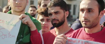 Movie still from “City of Ghosts” (2017), directed by Matthew Heineman – A group of young men standing next to each other on a street; Close Up shot, Low angle