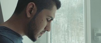 Movie still from “City of Ghosts” (2017), directed by Matthew Heineman – A person looking out of a window; Close Up shot, Low angle