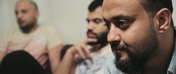 Movie still from “City of Ghosts” (2017), directed by Matthew Heineman – A man with a goatee is looking at a mirror; Close Up shot, Low angle