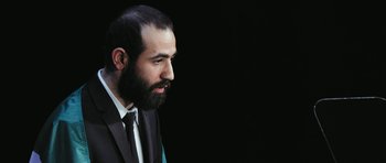 Movie still from “City of Ghosts” (2017), directed by Matthew Heineman – A man in a suit and tie looking to his left; Close Up shot, Low angle