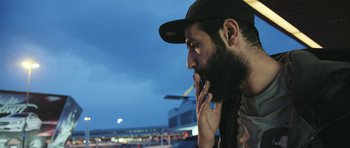 Movie still from “City of Ghosts” (2017), directed by Matthew Heineman – A man smoking a cigarette while sitting in a car; Close Up shot, Low angle