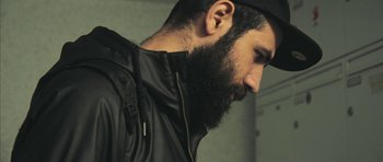 Movie still from “City of Ghosts” (2017), directed by Matthew Heineman – A man with a long beard and a hat on; Close Up shot, Low angle