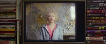 Movie still from “Climax” (2018), directed by Gaspar Noé – A woman with blonde curly hair sitting in front of a tv; Close Up shot, Over the shoulder angle