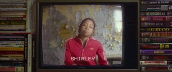 Movie still from “Climax” (2018), directed by Gaspar Noé – A woman in a red jacket sitting in front of a tv; Medium shot, Over the shoulder angle