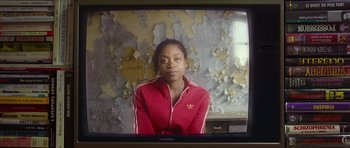 Movie still from “Climax” (2018), directed by Gaspar Noé – A young woman wearing a red jacket sitting in front of an old wall; Close Up shot, Over the shoulder angle