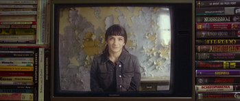 Movie still from “Climax” (2018), directed by Gaspar Noé – A young woman is smiling for the camera in front of an old wall; Close Up shot, High angle