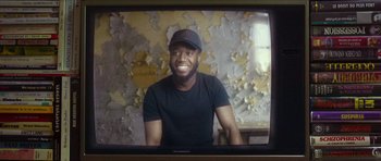 Movie still from “Climax” (2018), directed by Gaspar Noé – A man in black shirt and hat smiling for the camera; Medium shot, Low angle