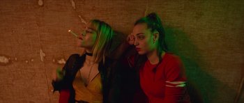 Movie still from “Climax” (2018), directed by Gaspar Noé – Two young women sitting next to each other smoking; Medium shot, Low angle