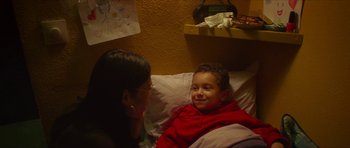 Movie still from “Climax” (2018), directed by Gaspar Noé – A young boy sitting in a bed with a woman; Medium shot, Over the shoulder angle