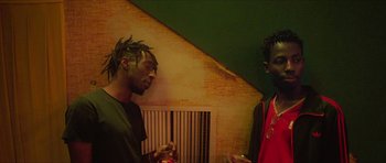 Movie still from “Climax” (2018), directed by Gaspar Noé – Two young men standing next to each other holding drinks; Medium shot, Low angle