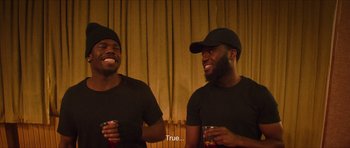 Movie still from “Climax” (2018), directed by Gaspar Noé – A couple of men sitting next to each other holding drinks; Medium shot, Over the shoulder angle