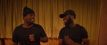 Movie still from “Climax” (2018), directed by Gaspar Noé – A couple of men standing next to each other holding drinks; Medium shot, High angle