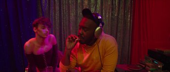 Movie still from “Climax” (2018), directed by Gaspar Noé – A man wearing headphones and eating a donut; Medium shot, Over the shoulder angle