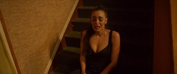 Movie still from “Climax” (2018), directed by Gaspar Noé – A woman sitting on the stairs crying; Medium shot, Overhead angle