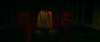 Movie still from “Climax” (2018), directed by Gaspar Noé – A woman with blonde hair is standing in a dark room; Medium shot, Low angle