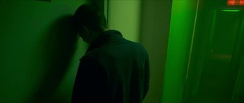 Movie still from “Climax” (2018), directed by Gaspar Noé – A man standing in front of a wall in a green room; Medium shot, Over the shoulder angle