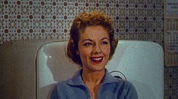 Movie still from “Cobain: Montage of Heck” (2015), directed by Brett Morgen – A woman sitting in a chair smiling for the camera; Close Up shot, Low angle