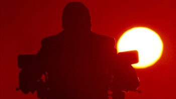 Movie still from “Cobra” (1986), directed by George P. Cosmatos – A person standing in front of a red sun; Wide shot, Low angle