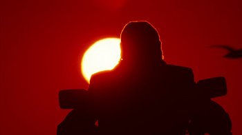 Movie still from “Cobra” (1986), directed by George P. Cosmatos – A person is standing in front of the setting sun; Medium shot, Low angle