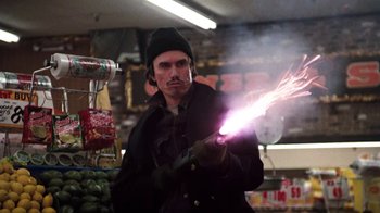 Movie still from “Cobra” (1986), directed by George P. Cosmatos – A man in a black jacket and a black hat is holding a sparkler in his hand; Medium shot, Low angle