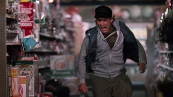 Movie still from “Cobra” (1986), directed by George P. Cosmatos – A man with a backpack walking through a store; Medium shot, Low angle