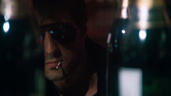 Movie still from “Cobra” (1986), directed by George P. Cosmatos – A person wearing sunglasses smoking a cigarette; Close Up shot, Low angle