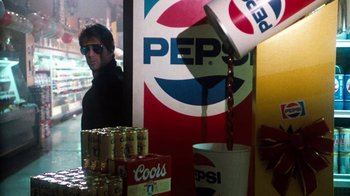 Movie still from “Cobra” (1986), directed by George P. Cosmatos – A man standing in front of a pepsi advertisement; Medium shot, Over the shoulder angle