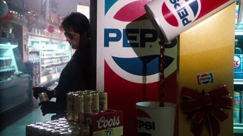 Movie still from “Cobra” (1986), directed by George P. Cosmatos – A man standing in front of a counter with a lot of soda cans; Medium shot, Over the shoulder angle
