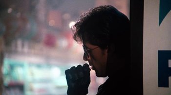 Movie still from “Cobra” (1986), directed by George P. Cosmatos – A man with glasses is looking out a window; Close Up shot, Over the shoulder angle