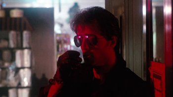 Movie still from “Cobra” (1986), directed by George P. Cosmatos – A man wearing sunglasses is holding a cell phone in his hand; Close Up shot, Low angle