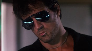Movie still from “Cobra” (1986), directed by George P. Cosmatos – A person wearing sunglasses; Close Up shot, Low angle