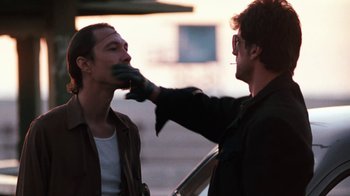 Movie still from “Cobra” (1986), directed by George P. Cosmatos – A man is shaving another man's face outside; Close Up shot, Over the shoulder angle