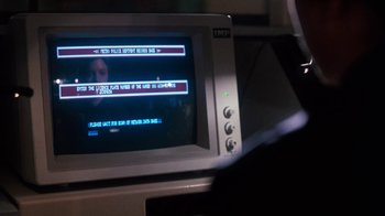 Movie still from “Cobra” (1986), directed by George P. Cosmatos – A computer monitor with a computer screen in the background; Extreme Close Up shot, Over the shoulder angle