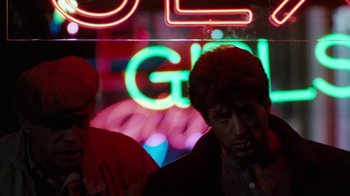 Movie still from “Cobra” (1986), directed by George P. Cosmatos – A man standing in front of a neon sign; Close Up shot, Over the shoulder angle