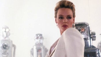 Movie still from “Cobra” (1986), directed by George P. Cosmatos – A woman in a white jacket posing for a picture; Close Up shot, Low angle