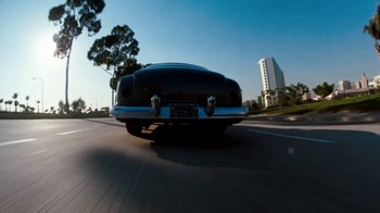 Movie still from “Cobra” (1986), directed by George P. Cosmatos – A car is driving down the street in the daytime; Wide shot, Low angle
