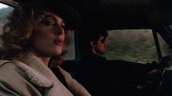 Movie still from “Cobra” (1986), directed by George P. Cosmatos – A man and a woman sitting in a car looking out the window; Close Up shot, Low angle
