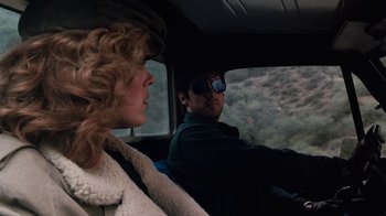 Movie still from “Cobra” (1986), directed by George P. Cosmatos – A man and a woman driving in a car; Close Up shot, Over the shoulder angle