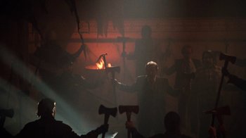 Movie still from “Cobra” (1986), directed by George P. Cosmatos – A group of people in a dark room with a microphone; Wide shot, Low angle