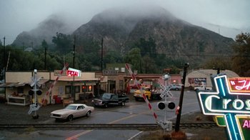 Movie still from “Cobra” (1986), directed by George P. Cosmatos – Cars are driving down the street in the rain; Extreme Wide shot, High angle