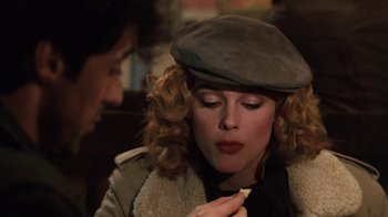 Movie still from “Cobra” (1986), directed by George P. Cosmatos – A woman in a hat is looking at a pencil; Close Up shot, Over the shoulder angle