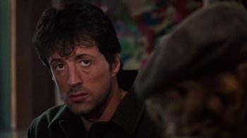Movie still from “Cobra” (1986), directed by George P. Cosmatos – Sylvester stallone in a scene from the movie rambo; Close Up shot, Over the shoulder angle
